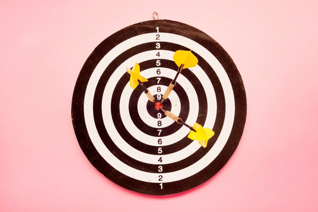 Dart board with three darts in the center point.